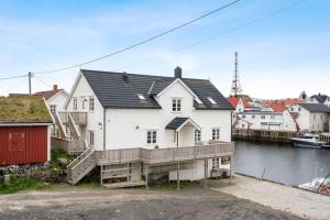 a large white house with a deck next to the water at Henningsvær Harbour Haven in Henningsvær