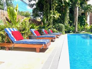 a row of chaise lounge chairs next to a swimming pool at TENDA Comfortable Apartments in Playa del Carmen