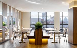 a restaurant with tables and chairs and large windows at Villano Hotel in Blumenau