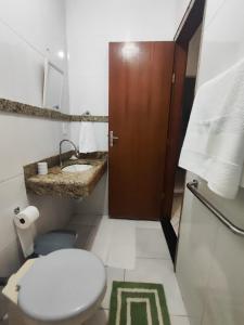 a white bathroom with a toilet and a sink at Temporada em Piúma in Piúma