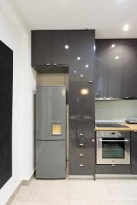 Una cocina con gabinetes negros y un refrigerador de acero inoxidable. en Aiolos Elegant retro suite in GLYFADA centre, en Atenas