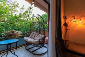 Un balcón con un columpio y una mesa en un porche. en Aiolos Elegant retro suite in GLYFADA centre, en Atenas