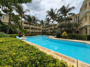 a swimming pool in front of a building with palm trees at Beach Bliss in our Bungalow in Flic-en-Flac