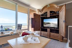 a living room with a tv and a table at Dünennest in Südstrand