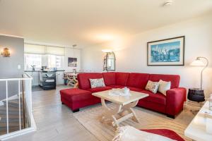 a living room with a red couch and a table at Dünennest in Südstrand