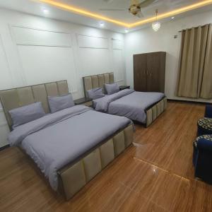 a room with two beds and a chair in it at Family Guest House Islamabad in Islamabad