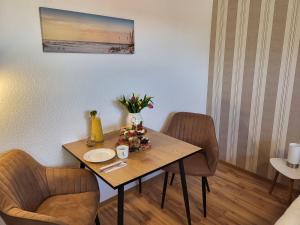 オストゼーバート・カールスハーゲンにあるFerienwohnung Graf kleine Auszeitのダイニングルームテーブル(椅子2脚、花のテーブル付)