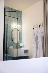 bagno con accappatoi bianchi appesi a un muro di Villa Lorenzo Chambres & Restaurant Barcelonnette Hotel a Barcelonnette Altre 37 foto