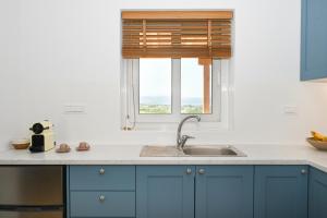 アダマスにあるAegean Blue - Volia Deluxe apartの青いキャビネット、シンク、窓付きのキッチン +24枚の写真