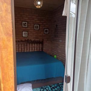 a bedroom with a blue bed in a doorway at Claudinha chalés in Conceição da Ibitipoca