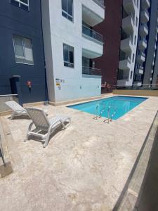 a swimming pool with two lounge chairs next to a building at comodo y acogedor apartamento in Sabaneta