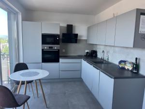 a kitchen with white cabinets and a table with chairs at Apartment Sun Lakes pri Aquaparku in Senec +24 photos