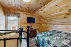 a log cabin bedroom with a bed and a tv at The Grouse House in Greenville