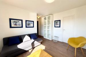 a living room with a black couch and a yellow chair at Charmant Studio - Bourg & plages à pied in Larmor-Plage