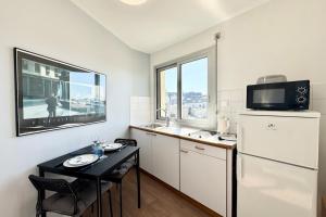a small kitchen with a table and a refrigerator at Charmant Studio - Bourg & plages à pied in Larmor-Plage