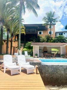 a patio with white chairs and a swimming pool at Vista dos sonhos na beira do mar de Angra com pier in Angra dos Reis