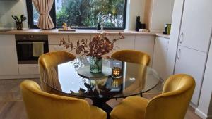 a kitchen with a glass table and yellow chairs at Aze - Green Business in Bucharest