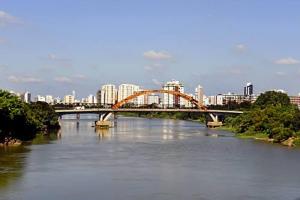 een brug over een rivier met een stad op de achtergrond bij Flat Aconchegante e Tranquilo in Campos dos Goytacazes