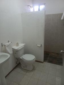 a white bathroom with a toilet and a sink at HOTEL VILLAS XAIBA in Puerto Escondido