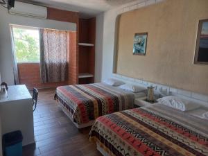 a hotel room with two beds and a window at HOTEL VILLAS XAIBA in Puerto Escondido