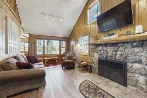 a living room with a stone fireplace with a flat screen tv at Stone Lake View in Manitowish Waters
