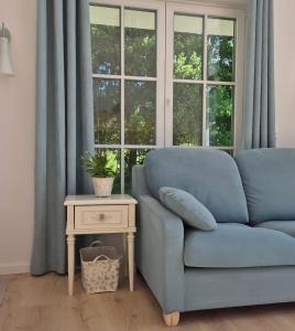 a blue couch in a room with a table and a window at Káli Pillangó - Ház a völgyben in Balatonhenye