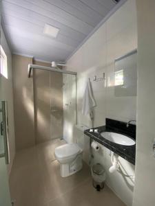 a white bathroom with a toilet and a sink at Executive Hotel Aguas lindas GO in Macacos +30 photos