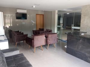 a lobby with a bunch of chairs and a television at Executive Hotel Aguas lindas GO in Macacos