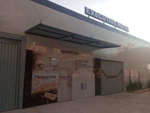 a building with a sign on the side of it at Executive Hotel Aguas lindas GO in Macacos