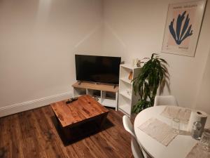 Una sala de estar con una mesa y un televisor. en Place to stay Croydon, en Thornton Heath