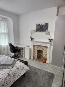 Un dormitorio con chimenea con un escritorio y una cama. en Place to stay Croydon, en Thornton Heath