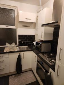Una cocina con gabinetes blancos, un fregadero y un microondas. en Place to stay Croydon, en Thornton Heath 12 fotos más