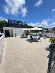 a patio with tables and chairs and umbrellas at Suites Premium 2 quartos in João Pessoa