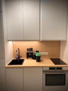 una cucina con armadi bianchi e lavandino di MIMIs Lakeside Apartment - NEWLY RENOVATED a Gmunden