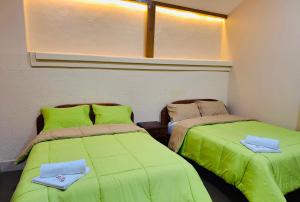 two beds in a room with green sheets at Travel Hotel Quito in Quito
