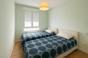two beds in a room with two windows at Apartamento centro con garaje in Castro-Urdiales
