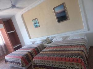 a hotel room with two beds and a television on the wall at HOTEL VILLAS XAIBA in Puerto Escondido