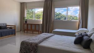a bedroom with two beds and two windows at Cobertura Duplex in São Lourenço