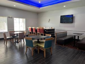 a waiting room with tables and chairs and a flat screen tv at Sonesta Essential North Houston in Houston