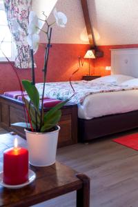 a bedroom with a bed and a candle on a table at Logis Auberge le centre poitou in Coulombiers