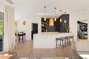 a kitchen and living room with a white counter and chairs at Baywaters Retreat by Sothebys Luxury Rental Homes in Closeburn