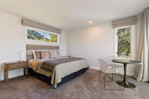 a bedroom with a bed and a table and two windows at Baywaters Retreat by Sothebys Luxury Rental Homes in Closeburn