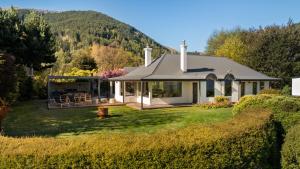 a white house with a hill in the background at Baywaters Retreat by Sothebys Luxury Rental Homes in Closeburn