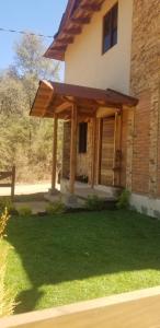 a house with a porch with a grass yard at Cabaña Arelys in Cedro