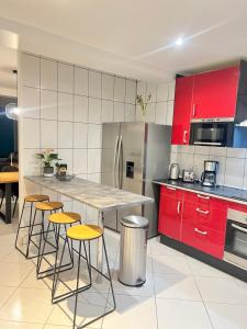 a kitchen with red cabinets and a table with stools at Maison Lumineuse à 15km de paris in Villiers-le-Bel