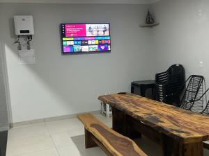 a room with a wooden table and a tv on the wall at Cantinho Guimarães in Olímpia