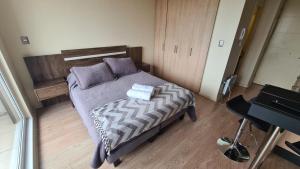 a bedroom with a bed with pillows and a piano at Departamento Estudio Central in Temuco +8 photos
