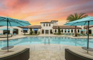 a pool with umbrellas in front of a building at Exceptional House 5BD4.5BA Private Pool WW8907 in Kissimmee