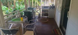 a porch with a table and chairs and a stove at Bungalow Évasion 6 in Sarraméa
