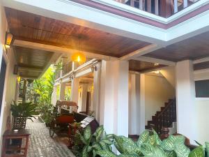 a house with a porch with a bunch of plants at Golden Sun Hotel in Luang Prabang